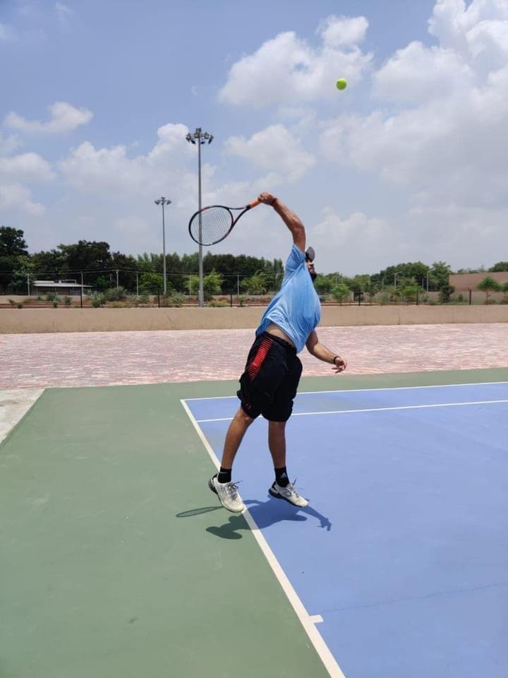 Tennis player serving on court at Nadiad Tennis Center, Gujarat